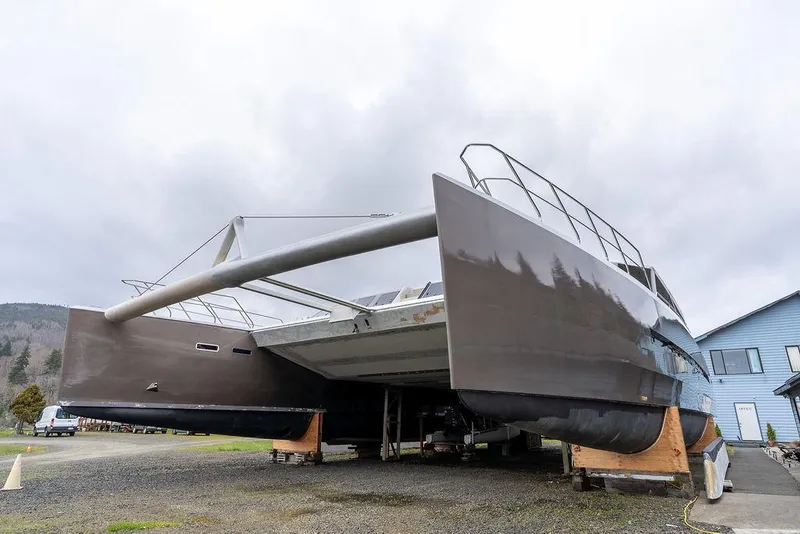 Slide: The Image of 2025 Catamaran Bloomfield 86 Motorsailor on land, showcasing sleek design and dual hulls. - 5