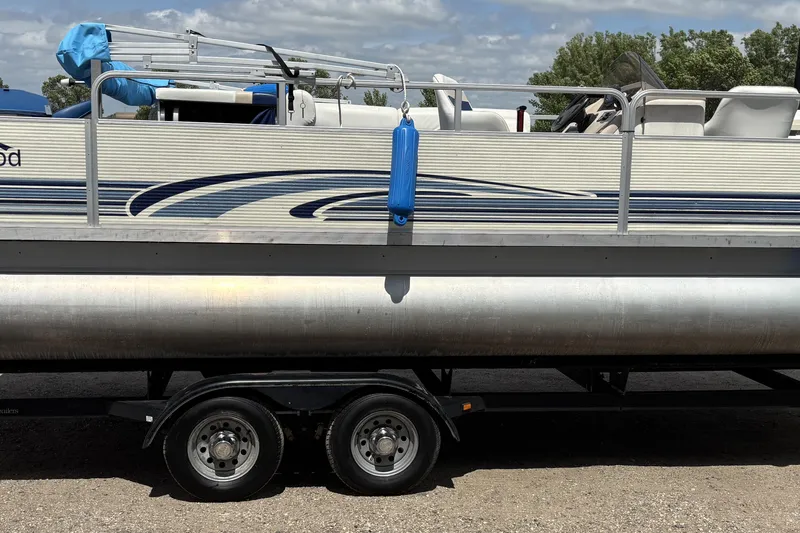 Slide: The Image of 1997 Northwood 24' Pontoon boat on trailer, featuring blue accents and outdoor seating. - 7