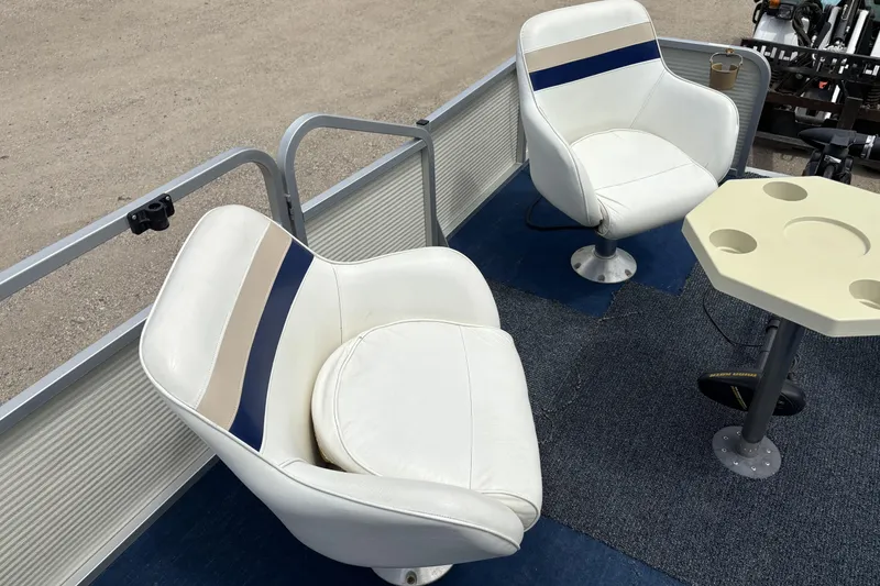 Slide: The Image of 1997 Northwood 24' Pontoon boat interior with white seats and a small table. - 14
