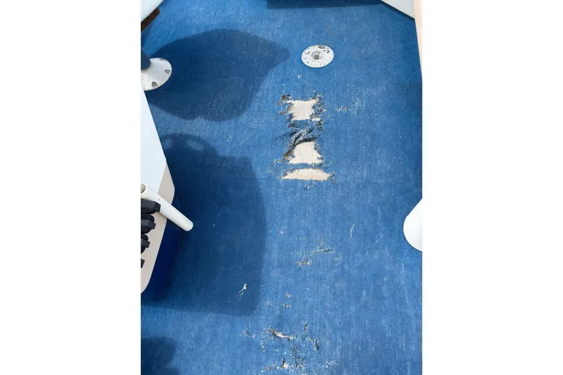 Slide: The Image of Worn blue carpet on 1997 Northwood 24' Pontoon boat floor, showing visible damage. - 9
