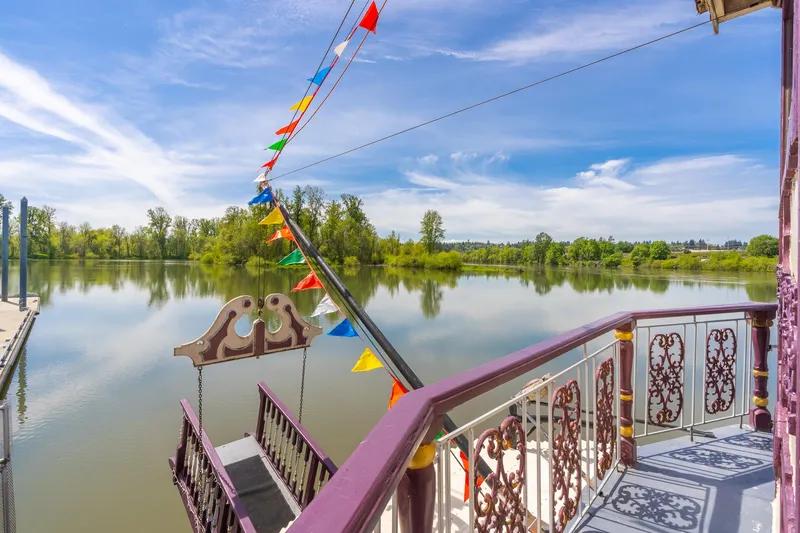 Slide: The Image of Colorful flags adorn a 1990 Custom Howdy Eidelman Sternwheeler on a serene river. - 42