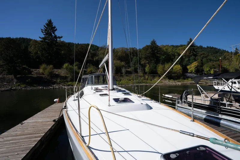 Slide: The Image of 2013 Beneteau Oceanis 50 sailboat docked, surrounded by lush greenery and calm waters. - 60
