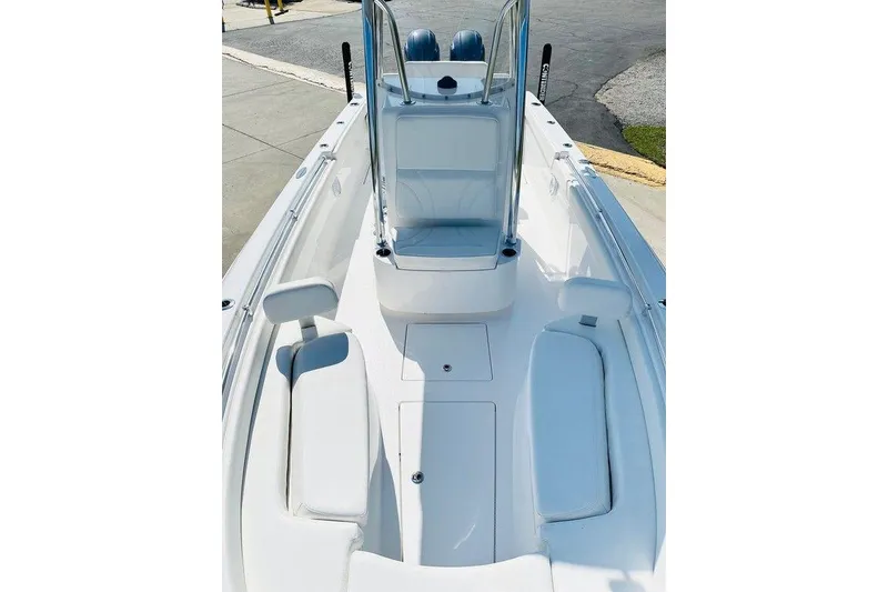 Slide: The Image of 2023 Contender 24 Sport boat interior with white seating and console, docked outdoors. - 13