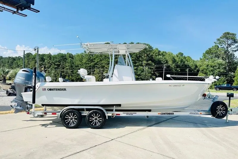 The Image of 2023 Contender 24 Sport boat on trailer, parked outdoors with trees in background. - 1