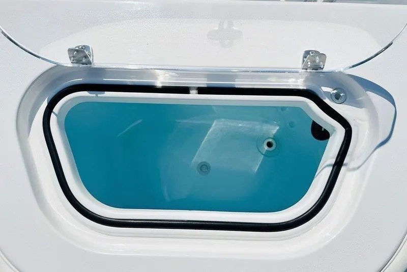 Slide: The Image of Livewell compartment on a 2023 Contender 24 Sport boat, featuring a clear lid and blue interior. - 7