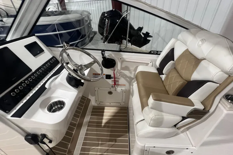 Slide: The Image of 2023 Edgewater 230CX Crossover boat interior with steering wheel and cushioned seating. - 10