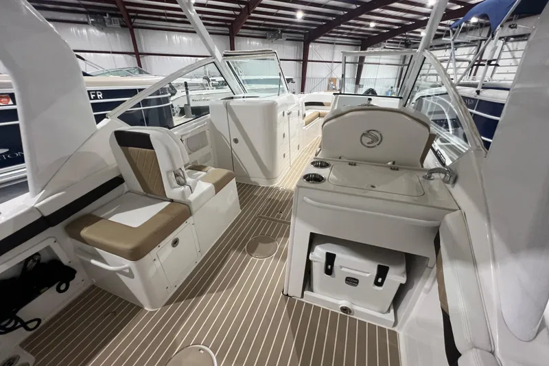 Slide: The Image of 2023 Edgewater 230CX Crossover boat interior with seating and storage in a showroom. - 8