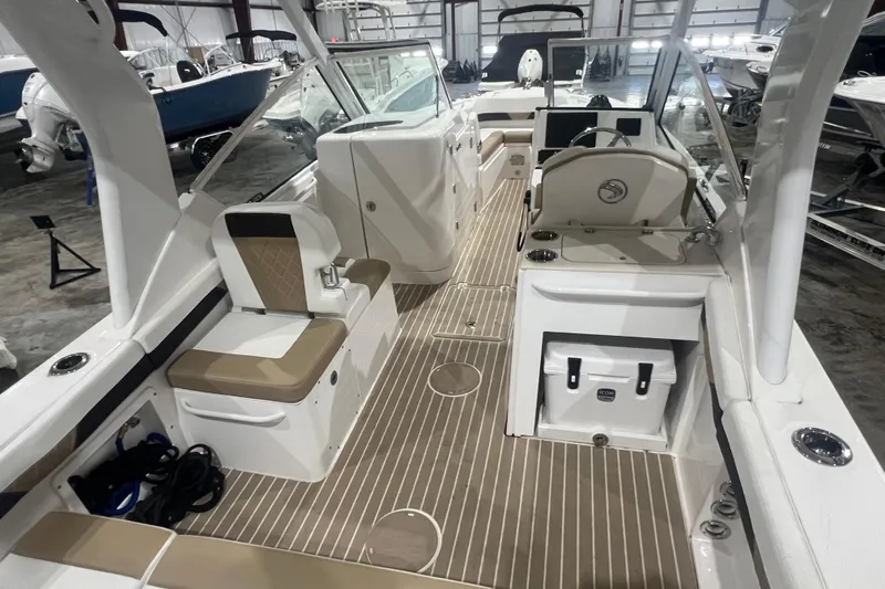 Slide: The Image of 2023 Edgewater 230CX Crossover boat interior with seating and helm in a showroom. - 5