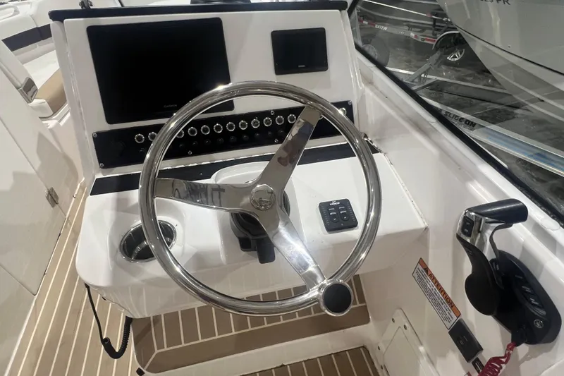 Slide: The Image of 2023 Edgewater 230CX Crossover boat helm with steering wheel and control panel. - 7