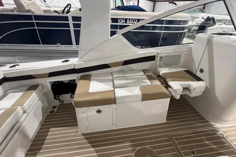 Slide: The Image of 2023 Edgewater 230CX Crossover boat interior with beige seating and wood-patterned flooring. - 14