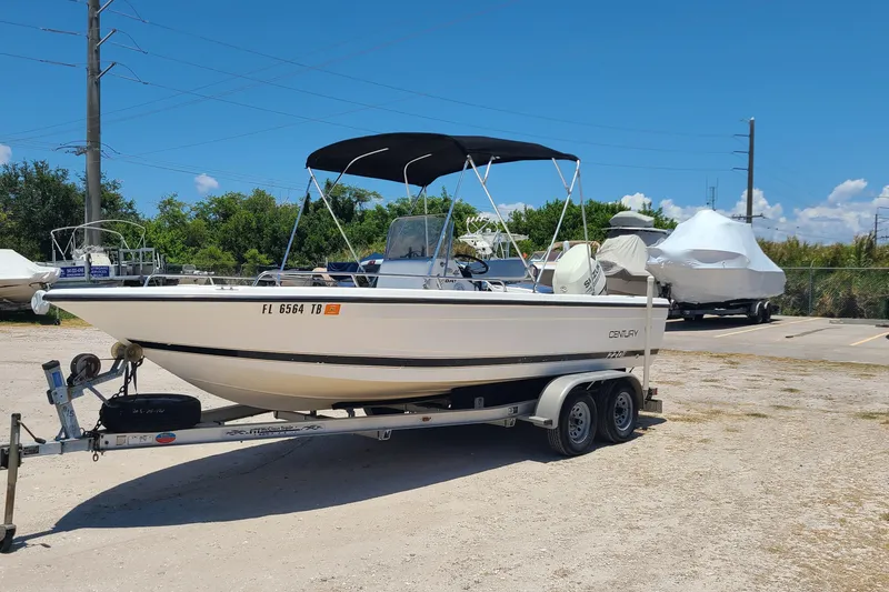 Slide: The Image of 2001 Century 2201 Bay Boat on trailer, parked outdoors under clear blue sky. - 2