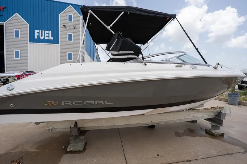 Slide: The Image of 2008 Regal 2000 Bowrider boat with canopy, displayed outdoors near a fuel station. - 7