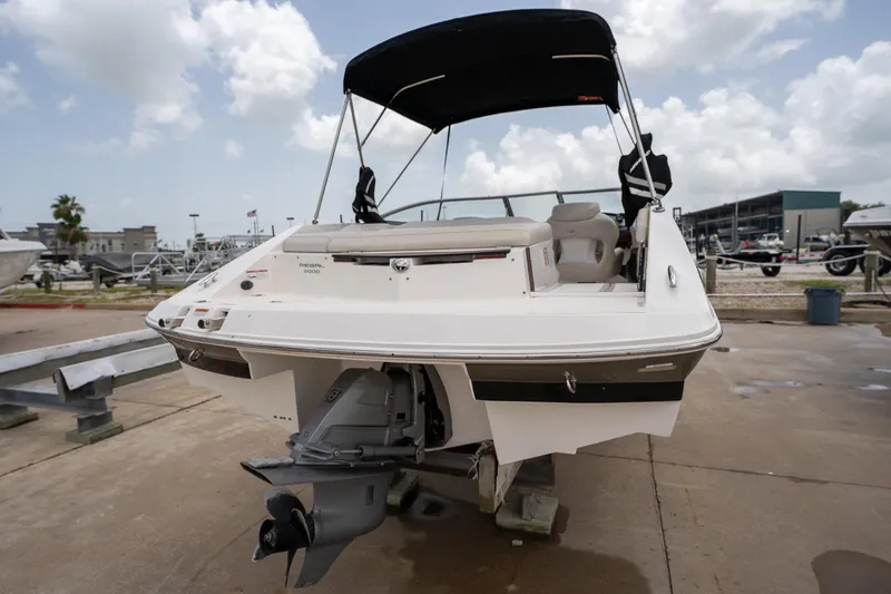 Slide: The Image of 2008 Regal 2000 Bowrider boat with canopy, parked on a concrete surface under cloudy skies. - 5