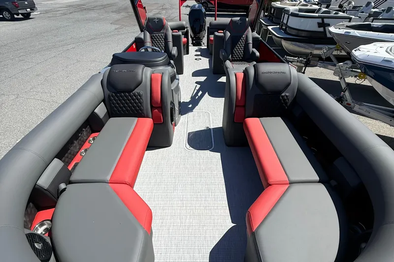 Slide: The Image of 2026 Berkshire 23RFX STS pontoon boat interior with red and gray seating, docked at marina. - 9