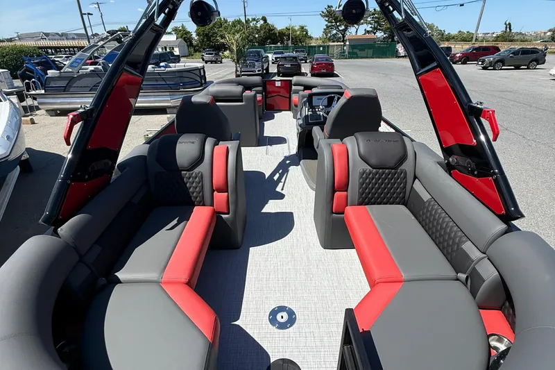 Slide: The Image of 2026 Berkshire 23RFX STS pontoon boat with luxurious red and gray seating, docked outdoors. - 11