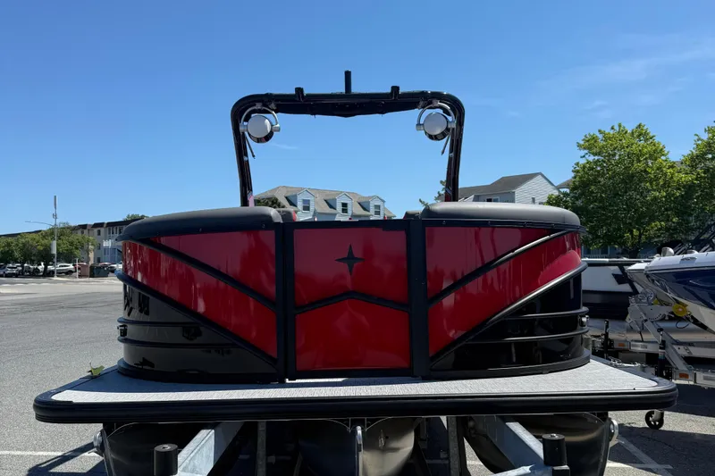 Slide: The Image of 2026 Berkshire 23RFX STS pontoon boat with sleek red and black design, parked outdoors. - 3