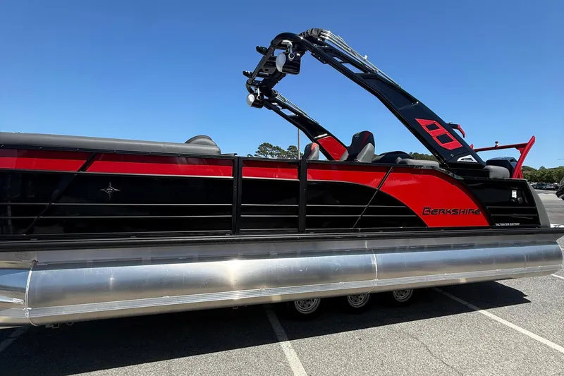 Slide: The Image of 2026 Berkshire 23RFX STS pontoon boat, sleek red and black design, parked outdoors. - 5