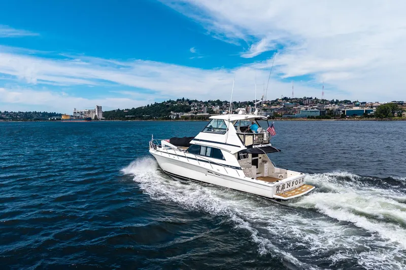 Slide: The Image of 1999 Riviera 48 Convertible yacht cruising on a scenic waterway under a clear blue sky. - 57