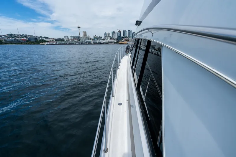 Slide: The Image of Side view of a 1999 Riviera 48 Convertible yacht cruising near a city skyline. - 60