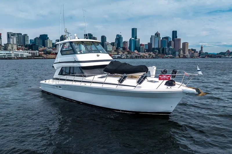 The Image of 1999 Riviera 48 Convertible yacht cruising near city skyline on a clear day. - 0