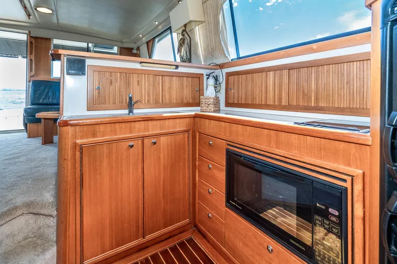 Slide: The Image of Luxurious 1999 Riviera 48 Convertible yacht interior with wooden cabinetry and modern kitchen amenities. - 38