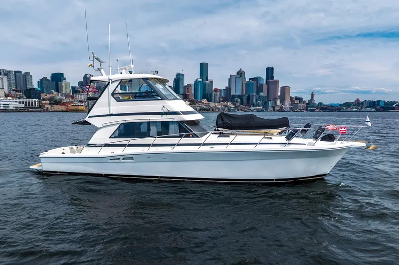 Slide: The Image of 1999 Riviera 48 Convertible yacht cruising near a city skyline on a clear day. - 4