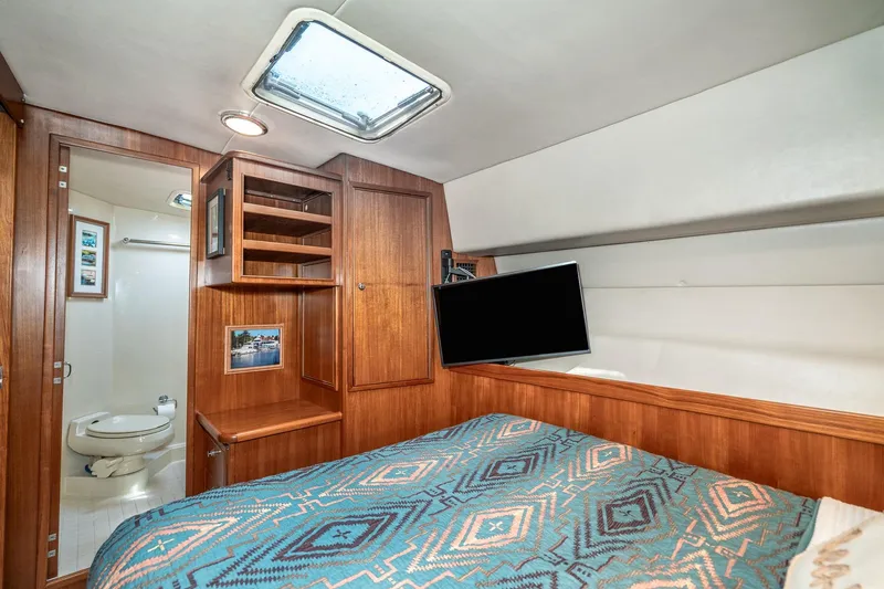 Slide: The Image of 1999 Riviera 48 Convertible yacht cabin with bed, TV, and ensuite bathroom. - 48