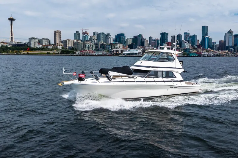 Slide: The Image of 1999 Riviera 48 Convertible yacht cruising near city skyline and iconic tower. - 2