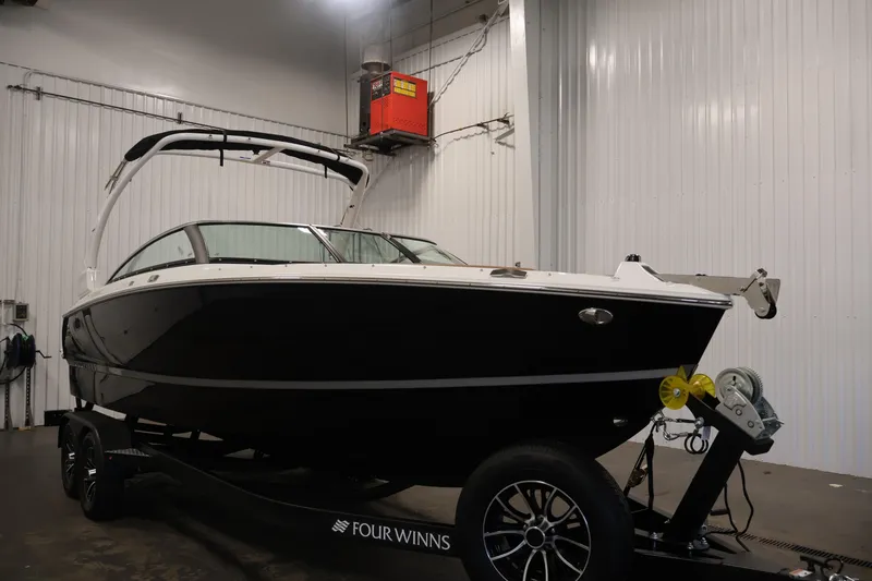 Slide: The Image of 2026 Four Winns H4 boat in a garage, black hull, on a trailer. - 2