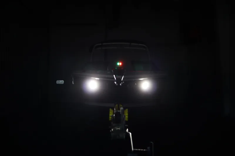 Slide: The Image of 2026 Four Winns H4 boat with headlights on in a dark setting. - 58