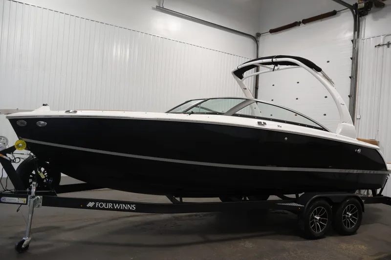 Slide: The Image of 2026 Four Winns H4 boat in showroom, black exterior, on trailer. - 7