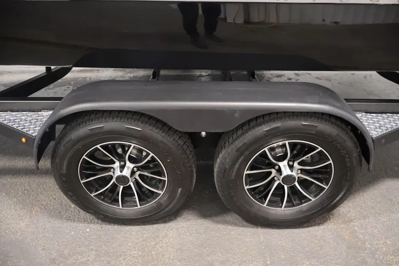 Slide: The Image of 2026 Four Winns H4 trailer with dual black alloy wheels on a textured surface. - 56