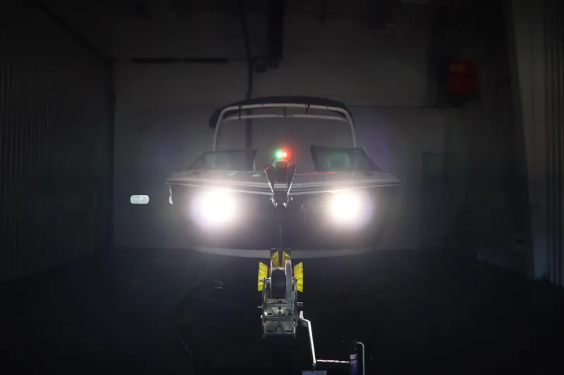 Slide: The Image of 2026 Four Winns H4 boat with headlights on in a dimly lit garage. - 59