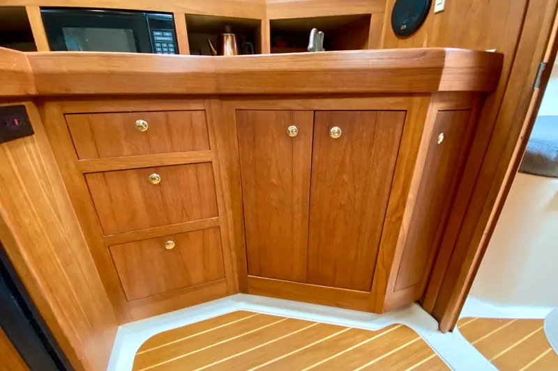 Slide: The Image of Wooden cabinetry in a 2002 Mainship Pilot 34 boat interior, featuring drawers and cupboards. - 31