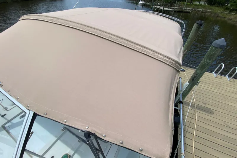 Slide: The Image of 2002 Mainship Pilot 34 boat with beige canopy docked by wooden pier. - 45