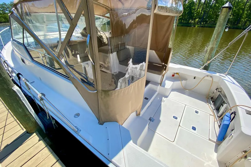 Slide: The Image of 2002 Mainship Pilot 34 boat docked, featuring spacious deck and protective canopy. - 7