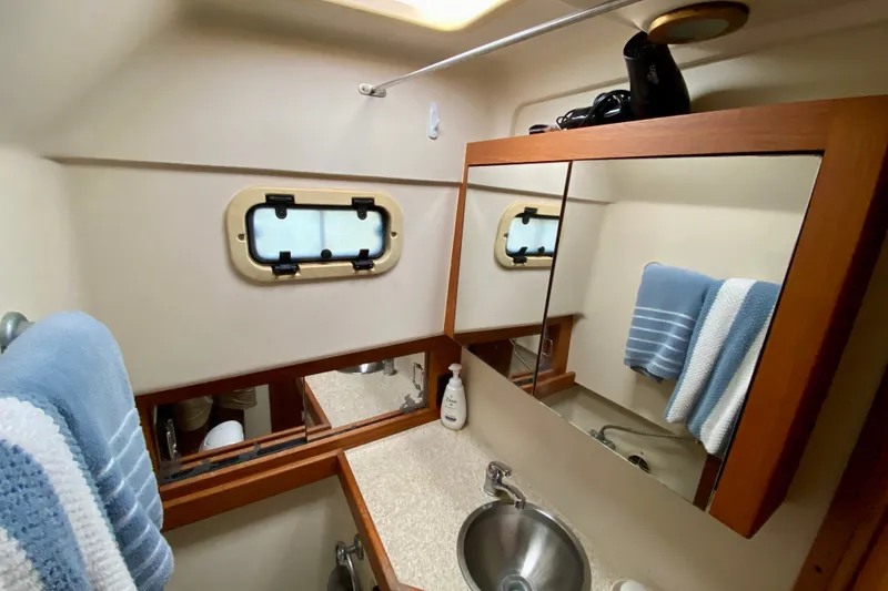 Slide: The Image of 2002 Mainship Pilot 34 bathroom with mirror, sink, and nautical window. - 25