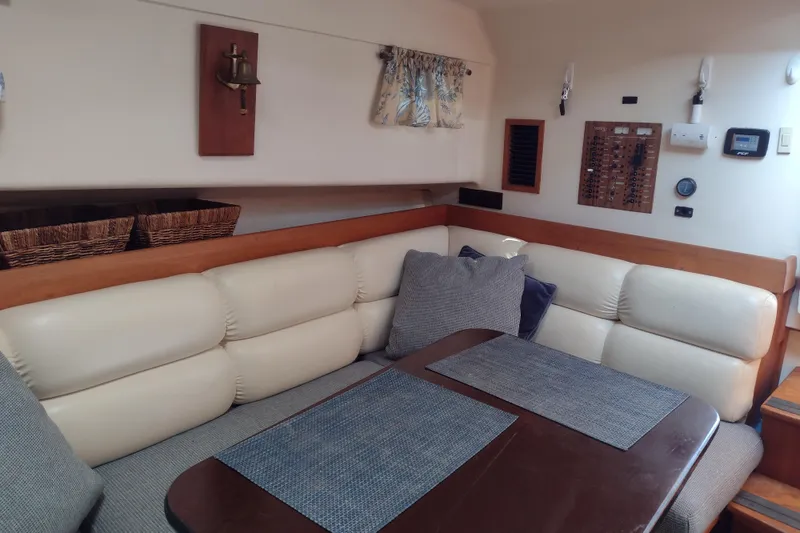 Slide: The Image of Interior of 2002 Mainship Pilot 34 with cushioned seating and dining area. - 2