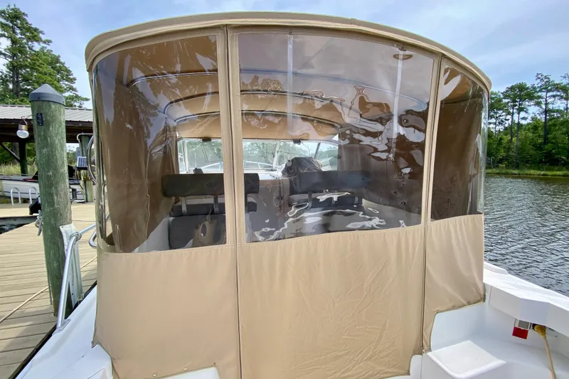 Slide: The Image of 2002 Mainship Pilot 34 boat with enclosed cockpit, docked by a serene lake. - 48