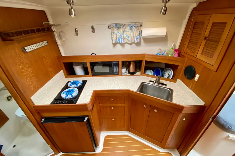 Slide: The Image of Compact kitchen in a 2002 Mainship Pilot 34 boat with wooden cabinetry and modern appliances. - 26