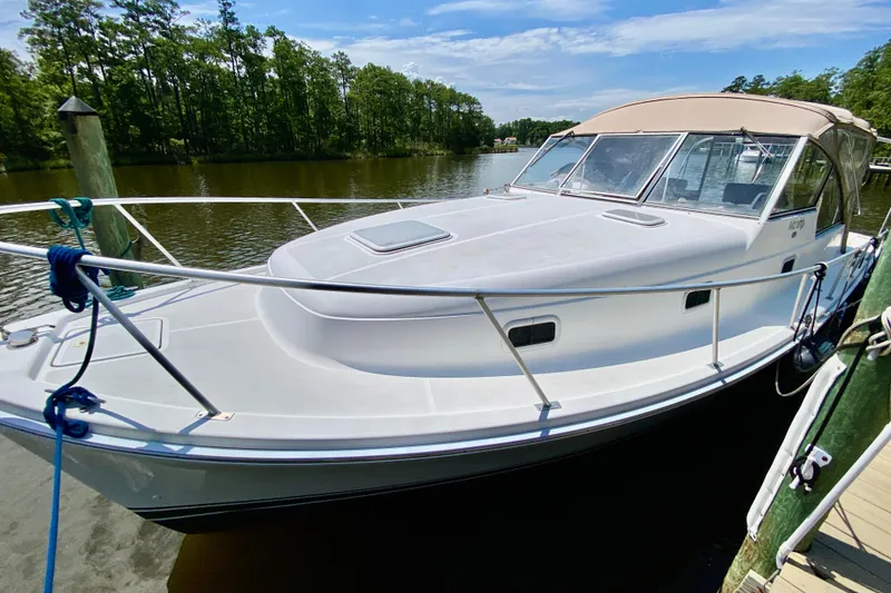 Slide: The Image of 2002 Mainship Pilot 34 docked on a serene river with lush greenery. - 3