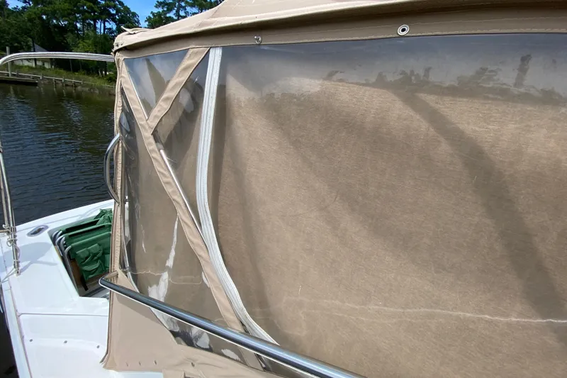 Slide: The Image of 2002 Mainship Pilot 34 boat with tan canvas enclosure on a calm waterway. - 42