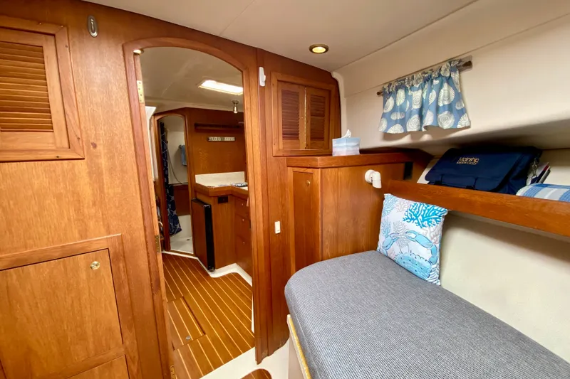 Slide: The Image of Interior of 2002 Mainship Pilot 34 boat, featuring cozy wooden cabinetry and nautical decor. - 35
