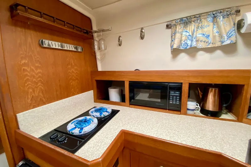 Slide: The Image of 2002 Mainship Pilot 34 galley with stove, microwave, and kettle. - 28