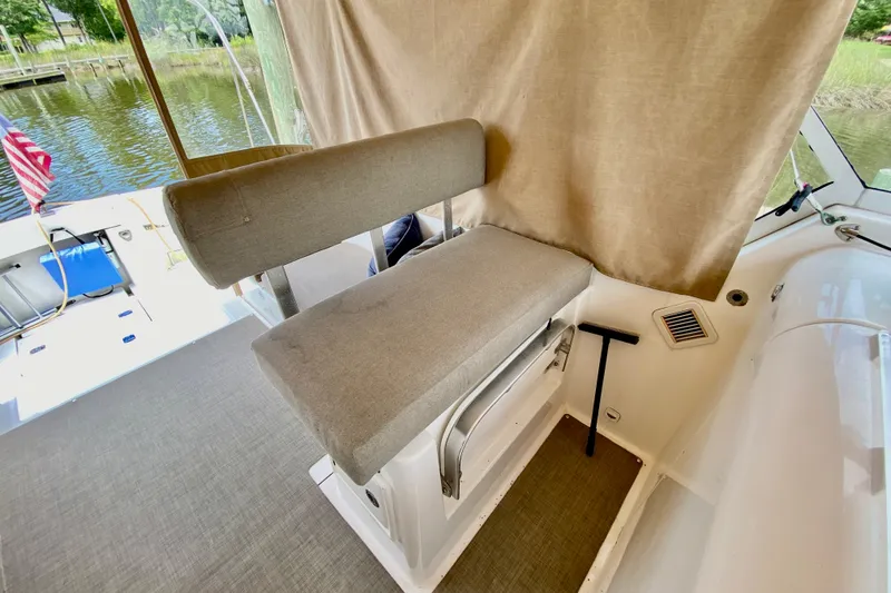 Slide: The Image of 2002 Mainship Pilot 34 boat interior with cushioned seating and window view. - 11