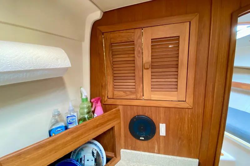 Slide: The Image of 2002 Mainship Pilot 34 interior with wooden cabinets and cleaning supplies. - 33