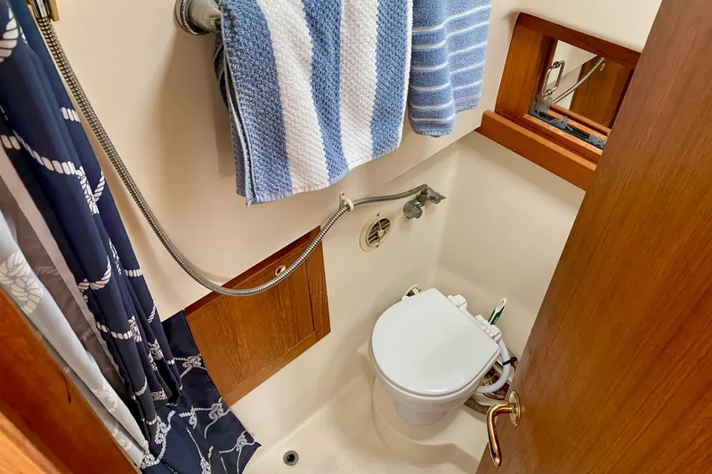 Slide: The Image of Compact bathroom in 2002 Mainship Pilot 34 boat with toilet, shower, and striped towel. - 23