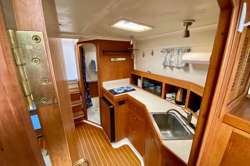 Slide: The Image of 2002 Mainship Pilot 34 interior with wooden cabinetry, compact kitchen, and modern amenities. - 17