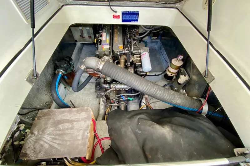 Slide: The Image of Engine compartment of a 2002 Mainship Pilot 34 boat, showcasing mechanical components and hoses. - 60