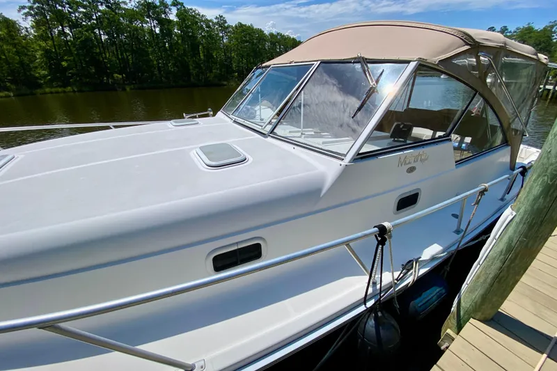 Slide: The Image of 2002 Mainship Pilot 34 docked by a serene river, featuring a sleek design and canopy. - 4